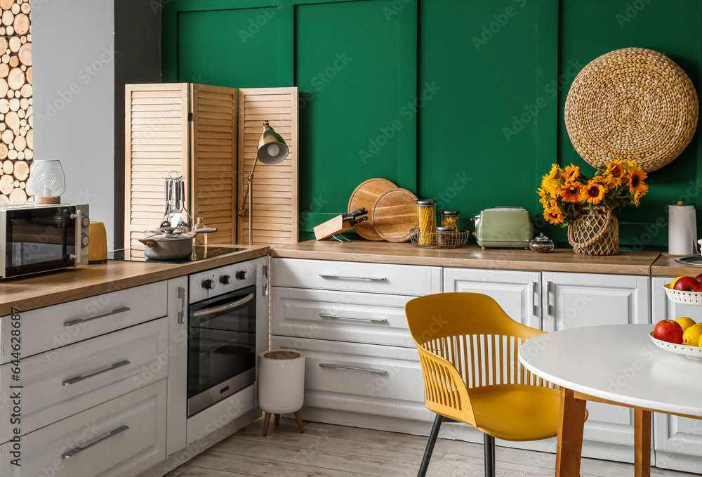 Interior of modern kitchen with white counters and dining table