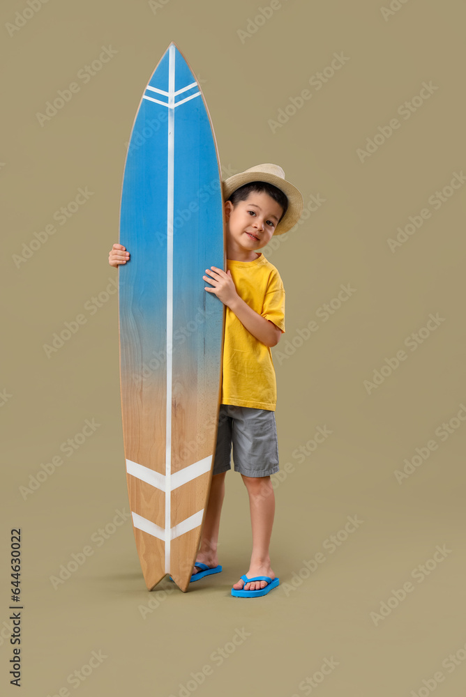 Cute little Asian boy with surfboard on green background