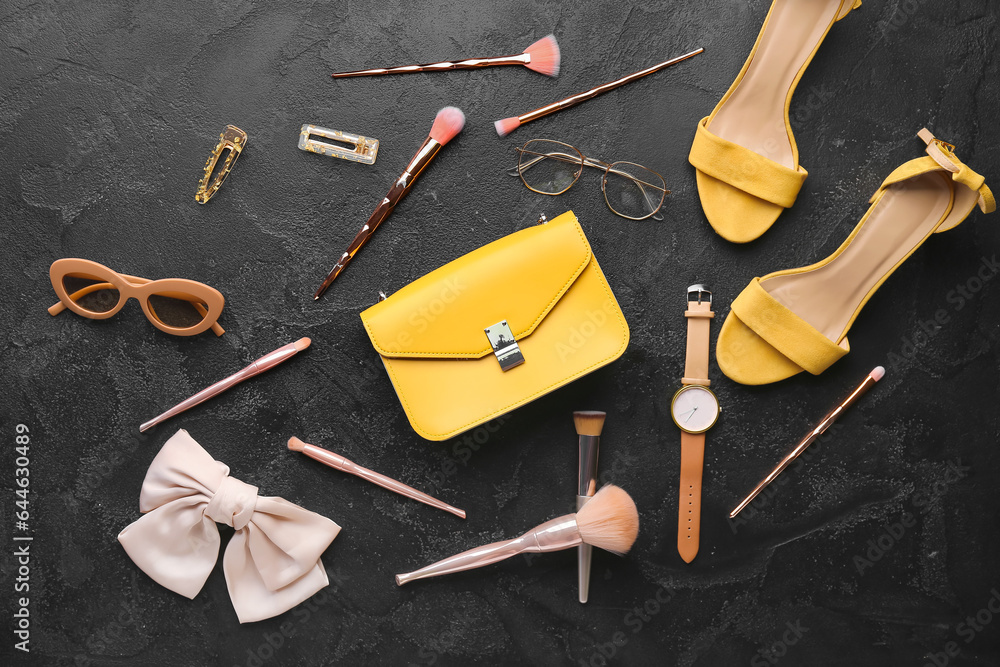 Composition with stylish female accessories and makeup brushes on dark background