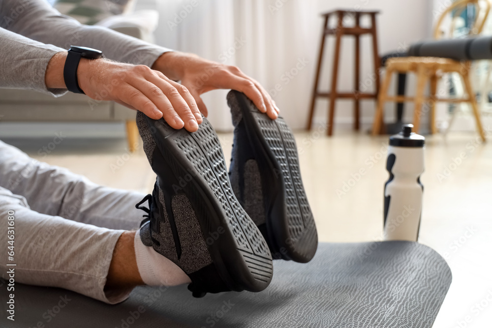 Sporty young man stretching at home