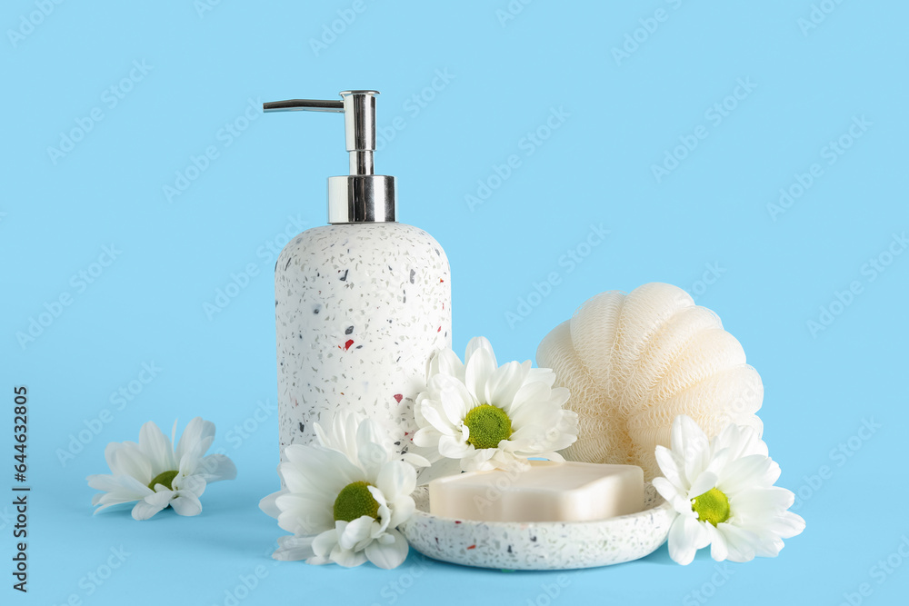 Bottle of cosmetic product, soap, bath sponge and chamomile flowers on color background