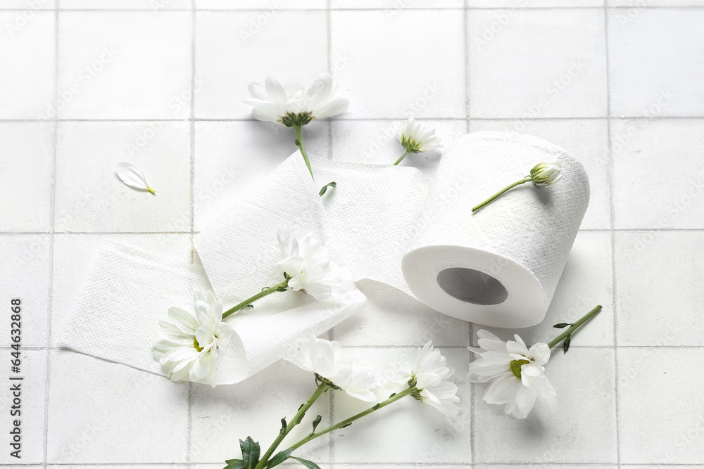 Composition with toilet paper roll and beautiful chamomile flowers on light tile background