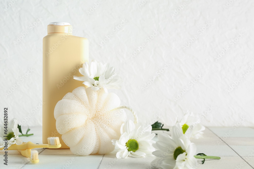 Composition with bath supplies and chamomile flowers on table against light background