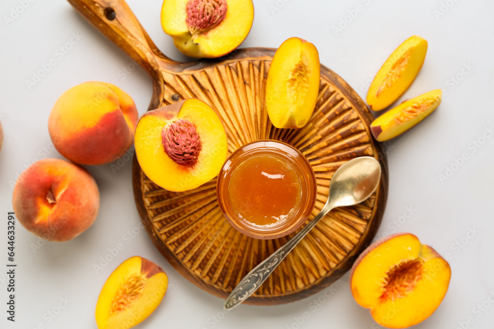 Wooden board with jar of tasty peach jam and fresh fruits on light background