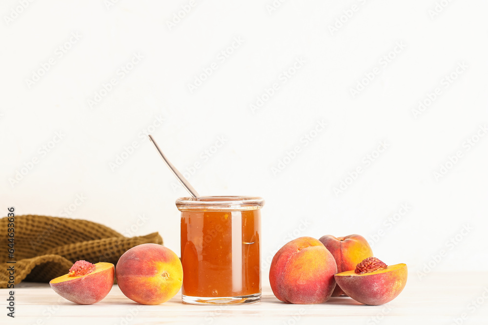 Jar with sweet peach jam and fresh fruits on table