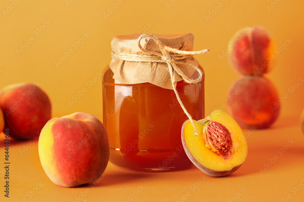 Jar with sweet peach jam and fresh fruits on orange background