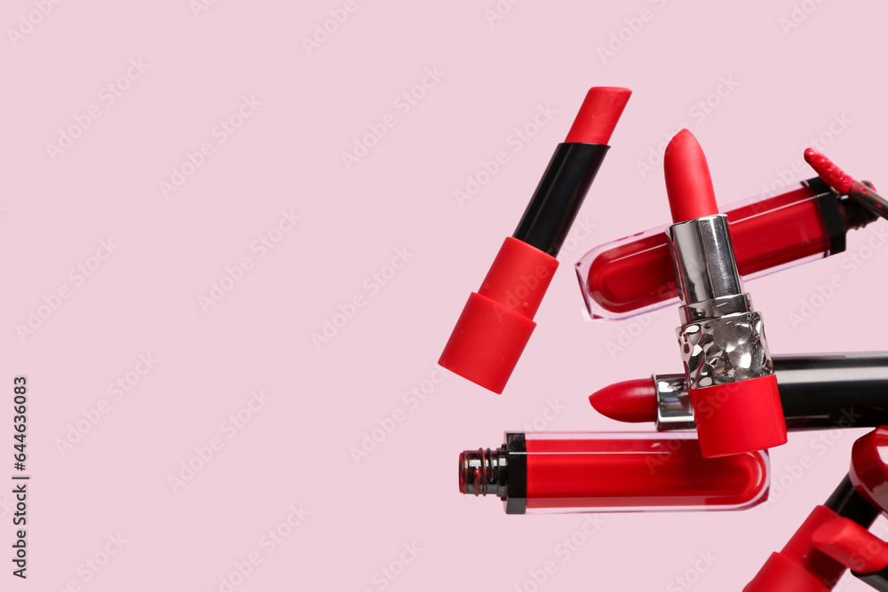 Different red lipsticks flying on pink background