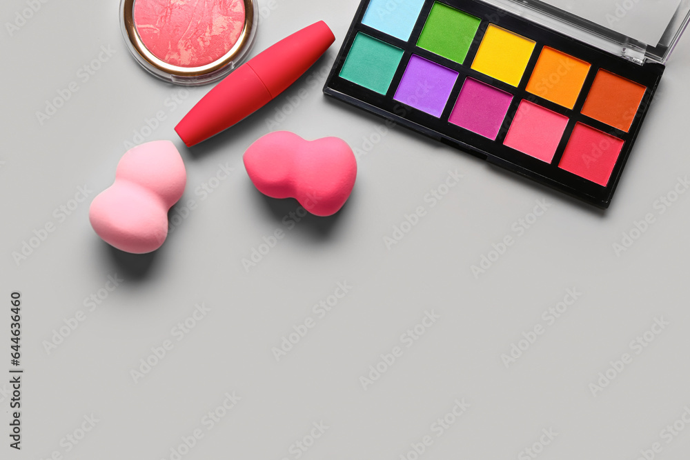 Set of decorative cosmetics and makeup sponges on grey background