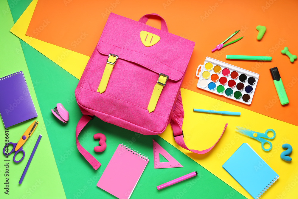 Composition with colorful school backpack and different stationery on color background