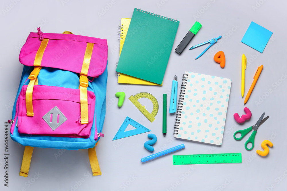 Composition with stylish school backpack and different stationery on grey background