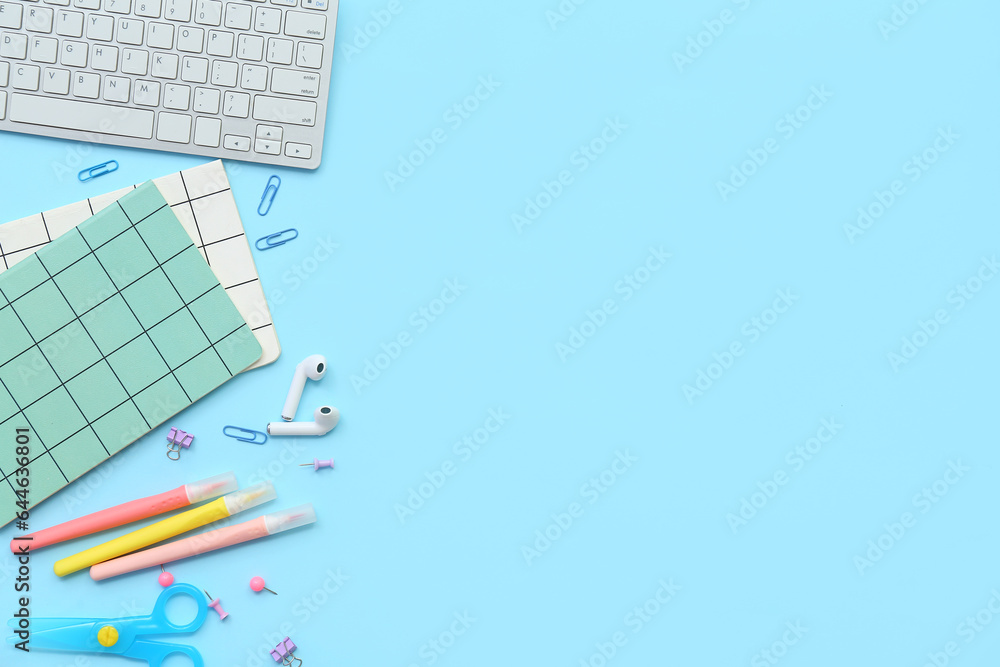 Composition with different stationery, earphones and keyboard on color background