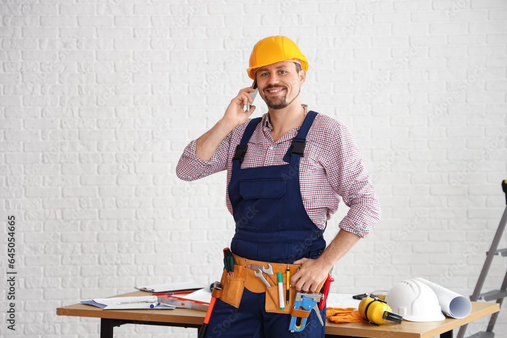 Male builder talking by mobile phone in room