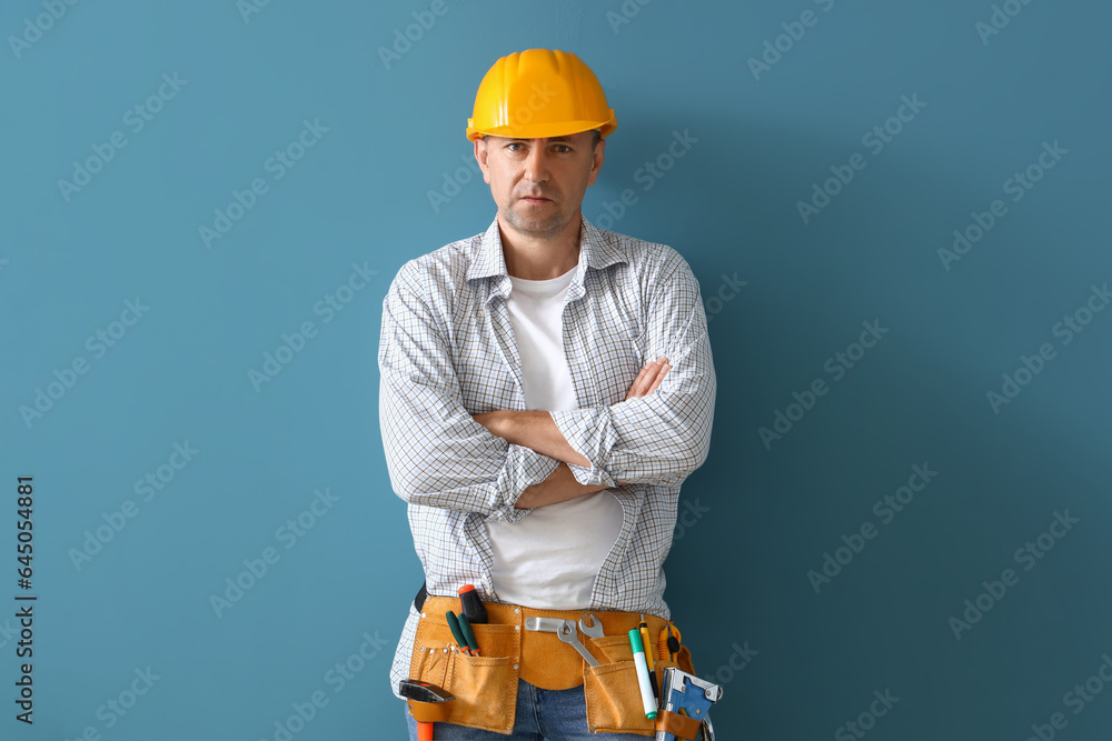 Mature builder with tool belt on blue background