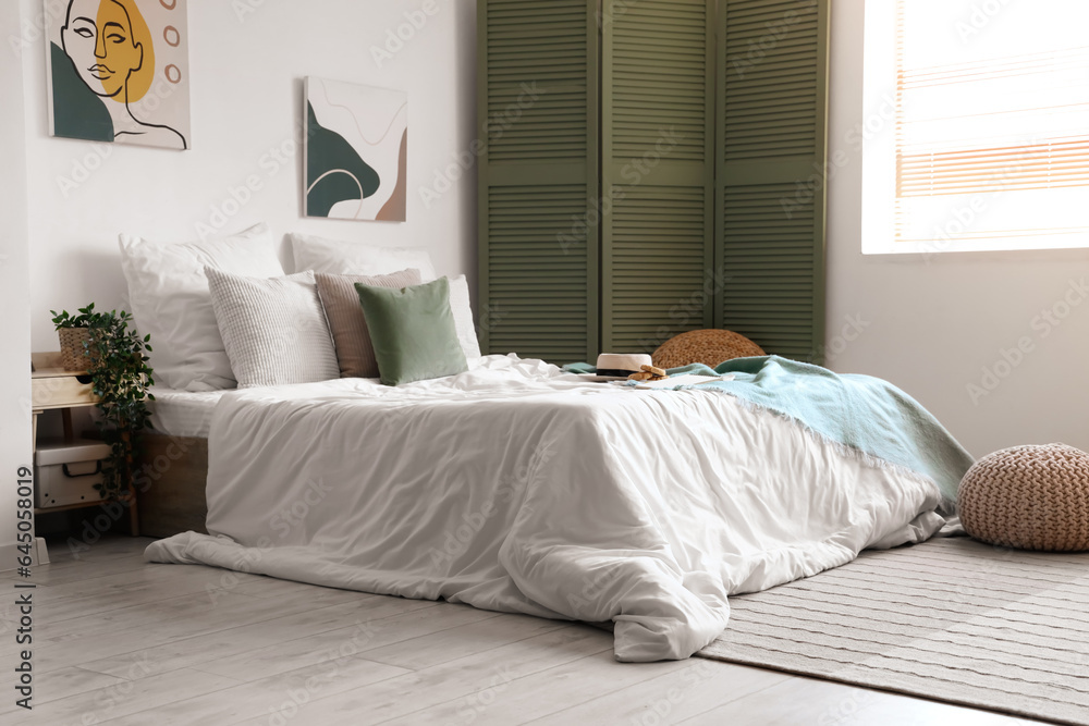 Cozy bed with white blanket, hat and cookies in stylish bedroom