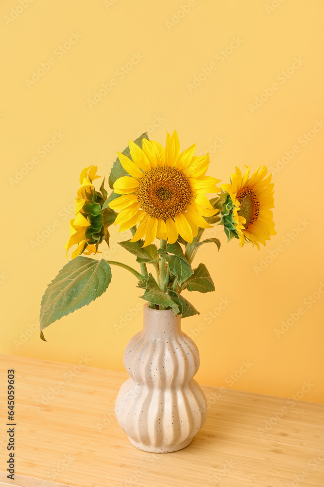 Vase with sunflowers on table near color wall