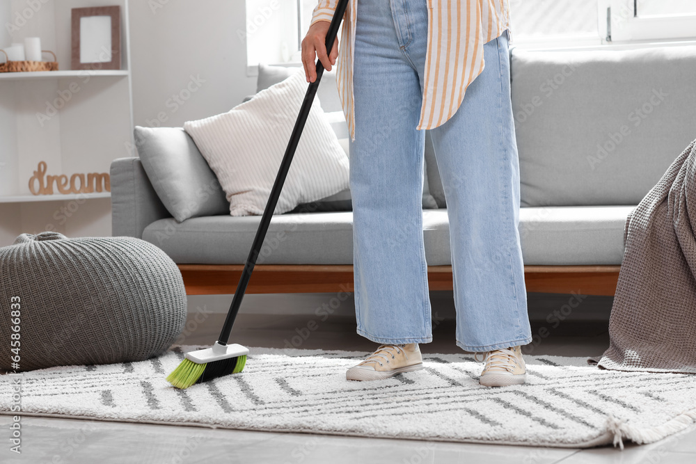 Mature woman sweeping floor in room