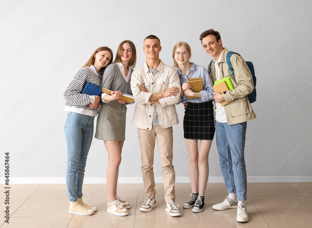 Group of students with books near grey wall