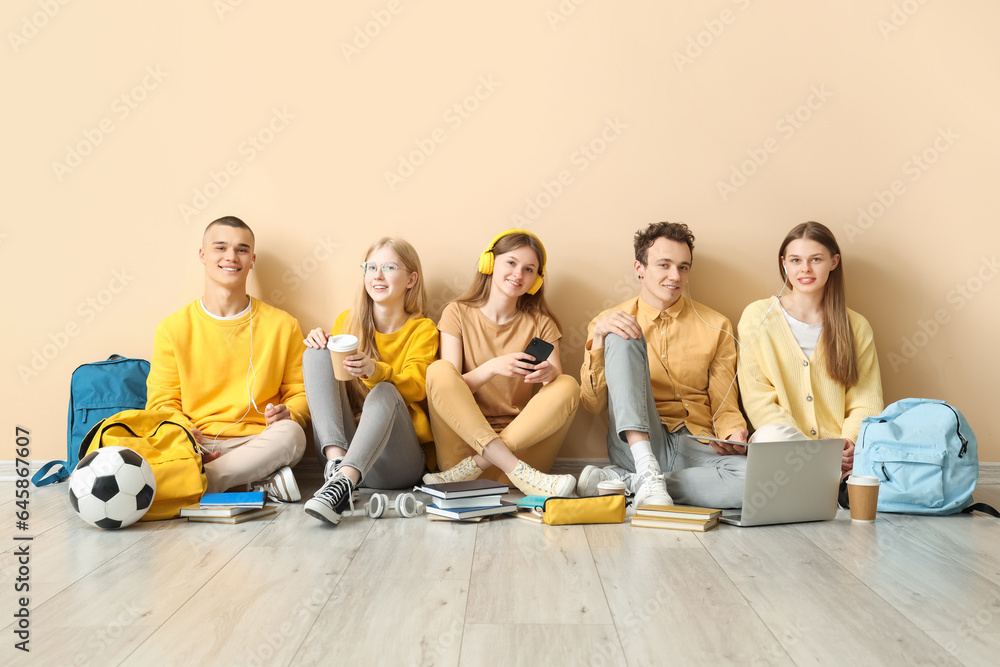 Group of students sitting on floor near yellow wall