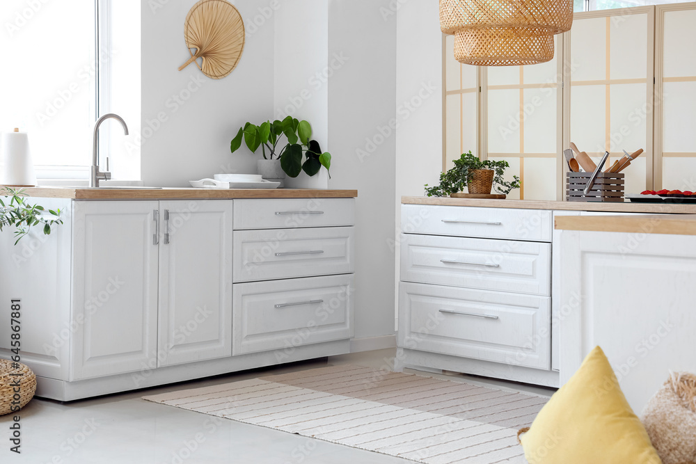 Interior of light kitchen with white counters near window