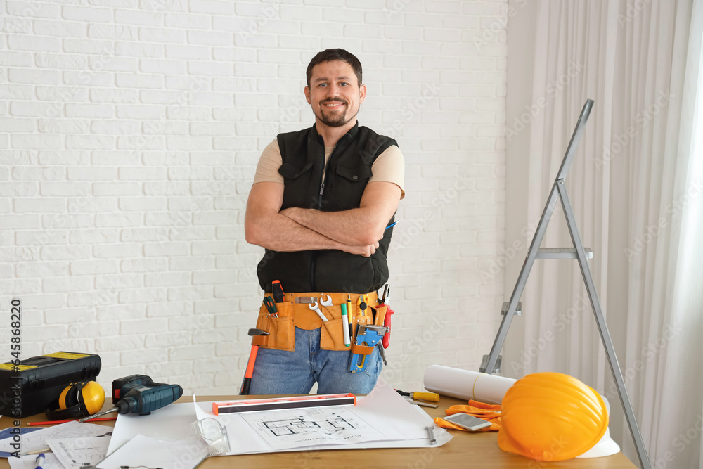 Male builder working at table in room