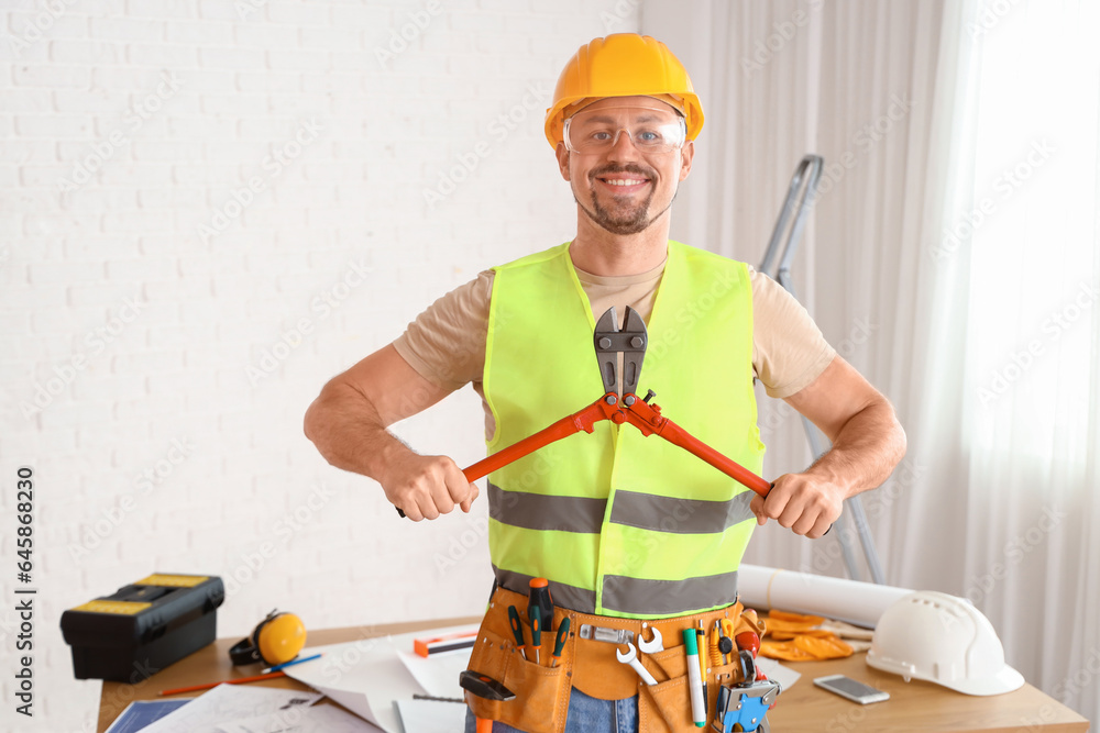 Male builder with pliers in room