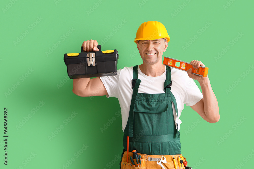 Mature builder with tool bag on green background