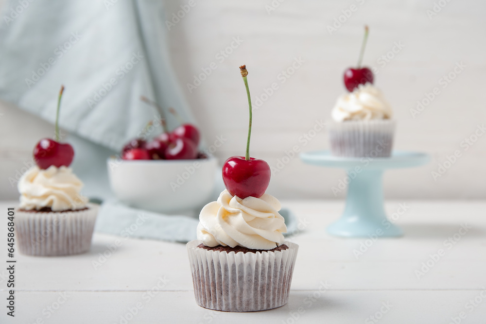 Tasty cherry cupcakes on table