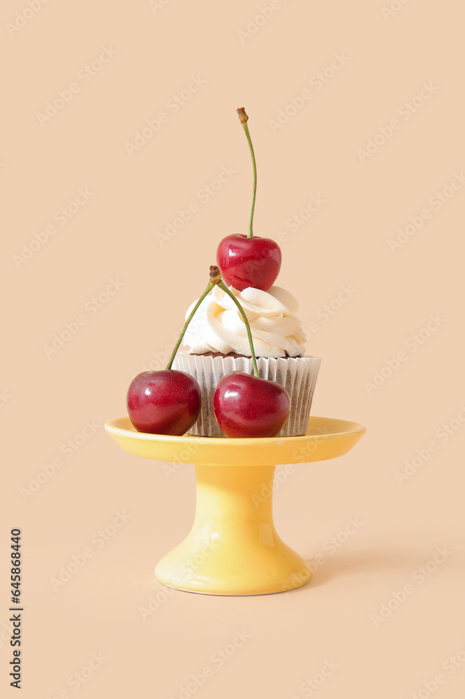 Stand with tasty cherry cupcake on beige background