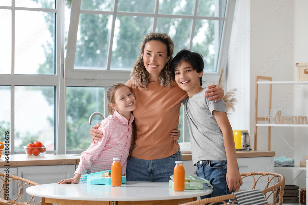 Mother hugging her little children before school in kitchen