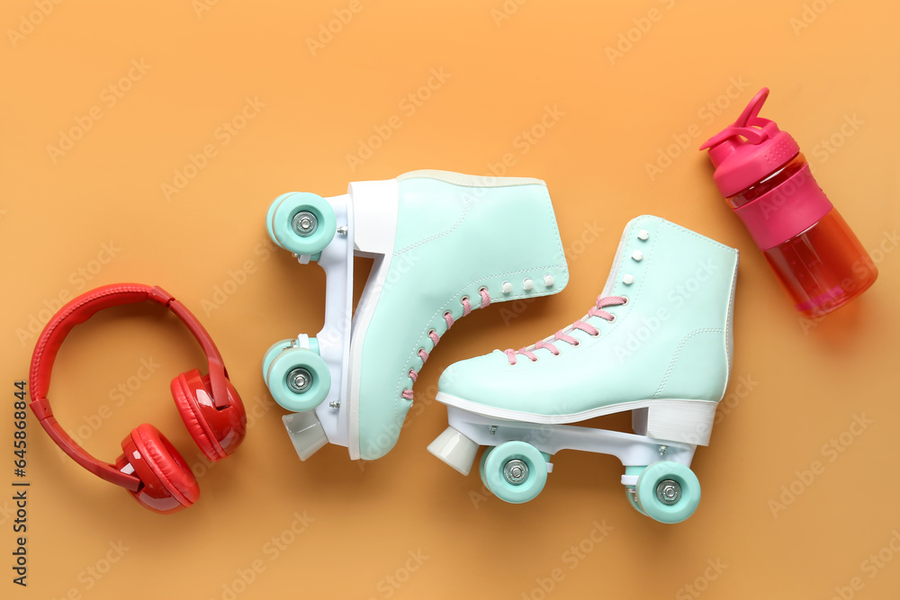 Roller skates, headphones and bottle of water on color background