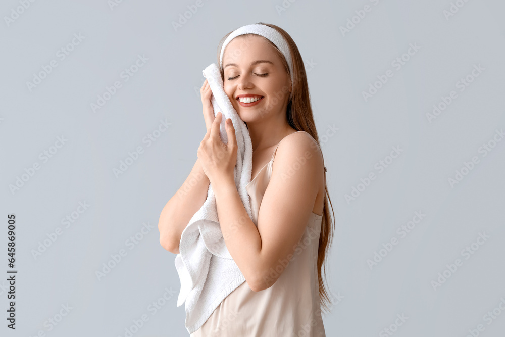 Pretty young woman with soft towel on light background