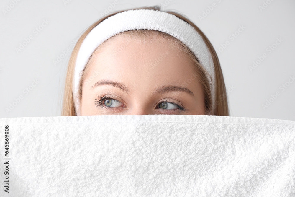 Pretty young woman with soft towel on light background