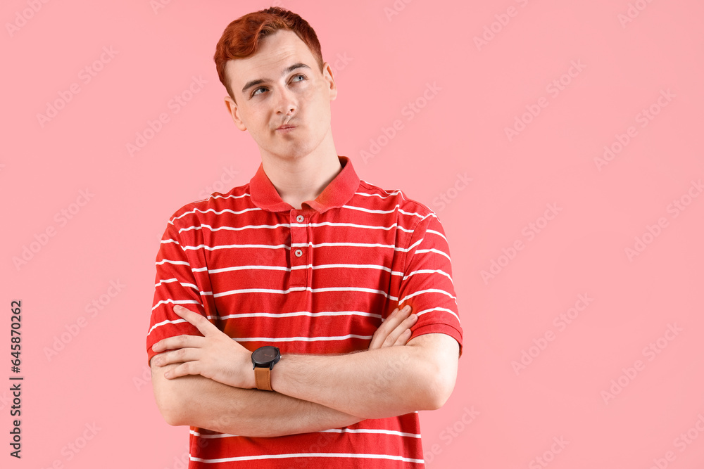 Thoughtful young redhead man with wrist watch on pink background