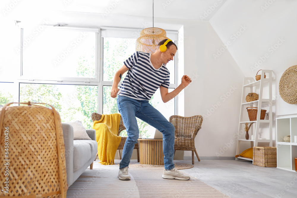 Young man in headphones dancing at home