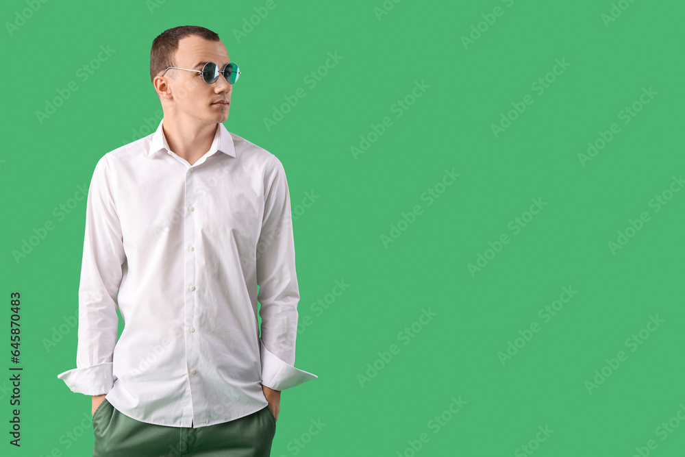 Young man in sunglasses on green background