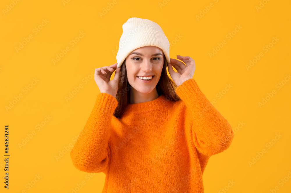 Young woman in winter clothes on yellow background