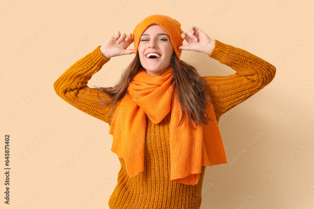 Young woman in winter clothes on beige background