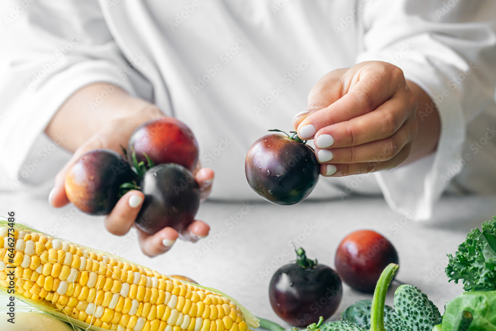 Black tomatoes in female hands close-up, cooking in the kitchen.