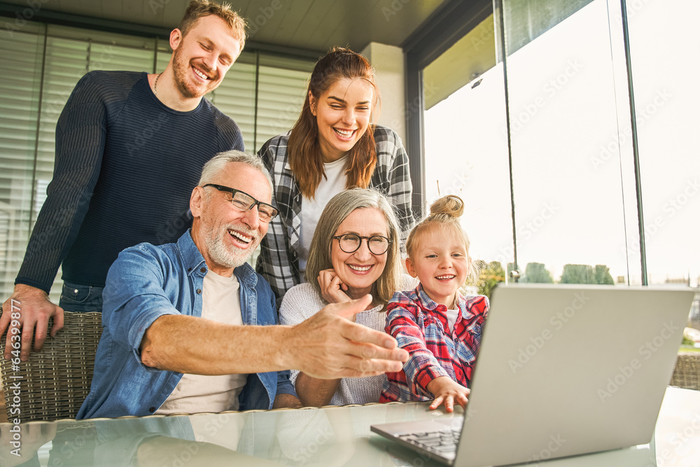 Overjoyed family having video call on laptop during breakfast