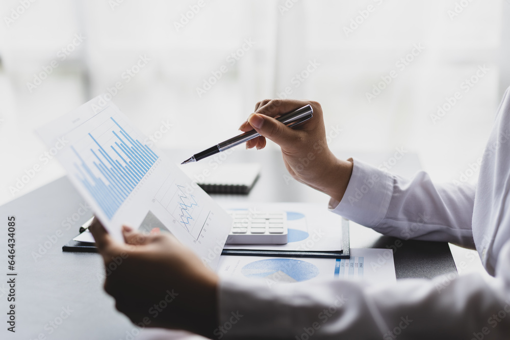 Businesswoman working on documents analyzing business finance charts and planning investments.