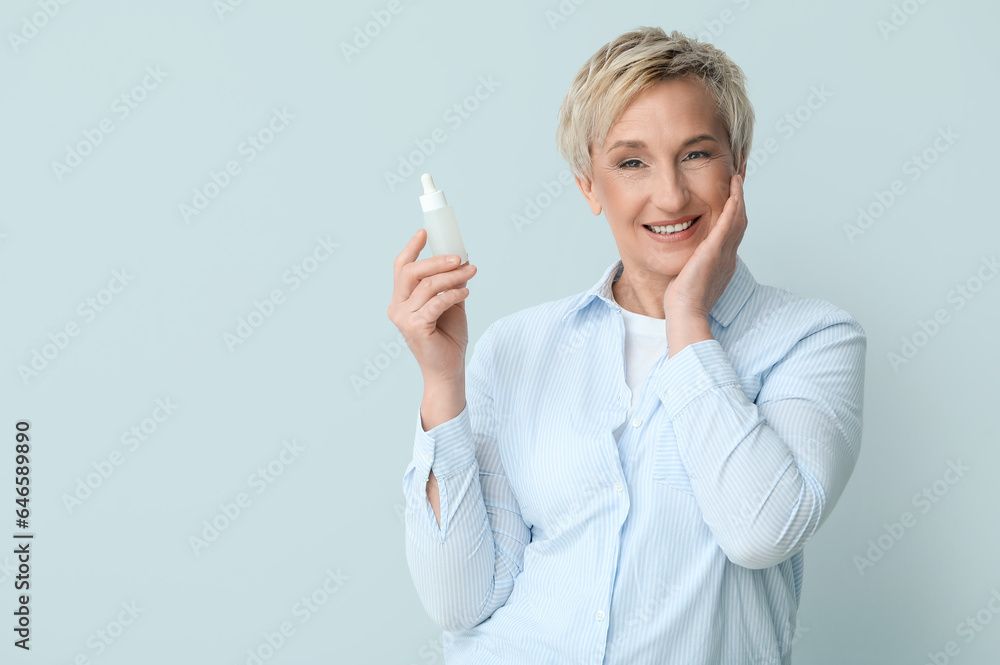 Mature woman with bottle of serum on light background