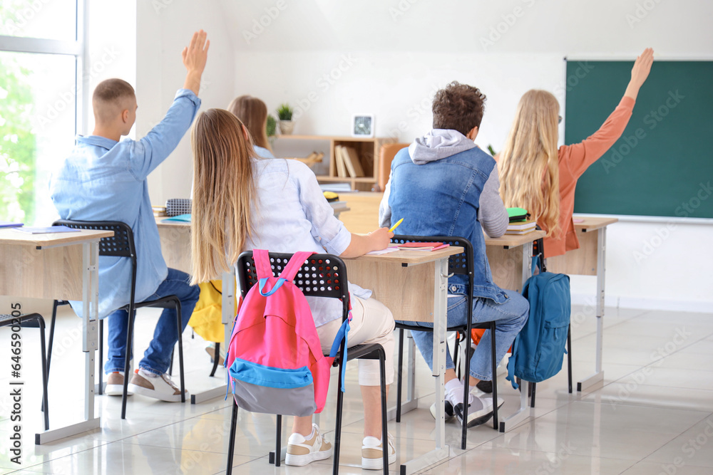 Classmates raising hands to answer in classroom