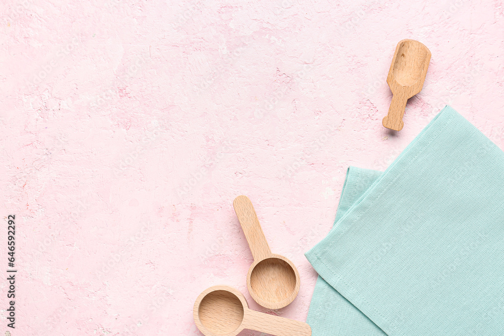 Wooden kitchen utensils and clean napkin on color background