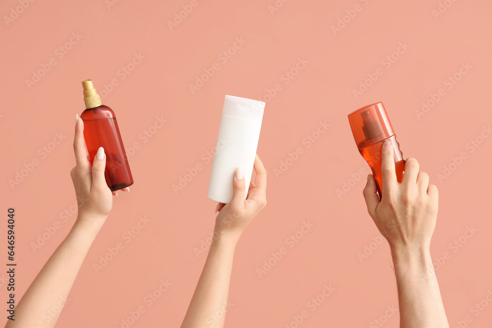 Female hands with bottles of sunscreen cream on color background