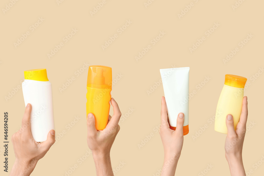 Female hands with bottles of sunscreen cream on beige background