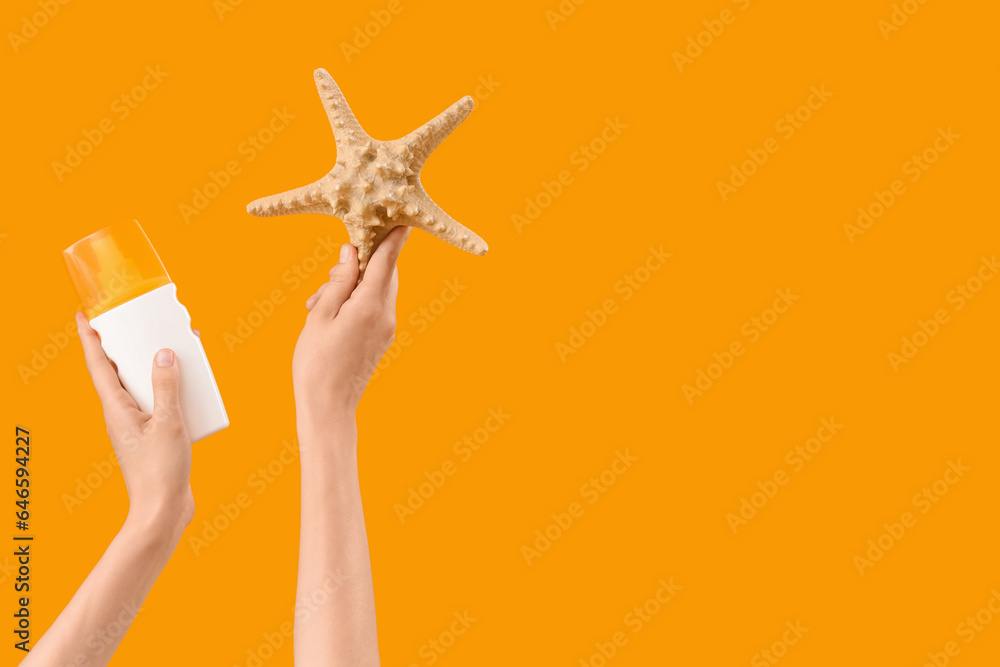 Female hands with bottle of sunscreen cream and starfish on yellow background