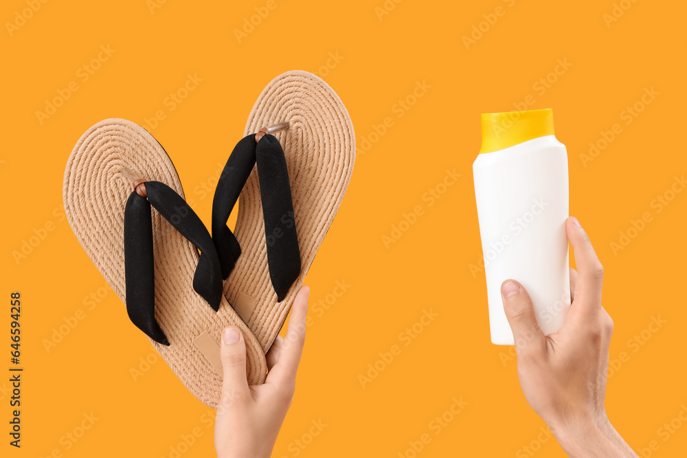 Female hands with bottle of sunscreen cream and flip flops on yellow background