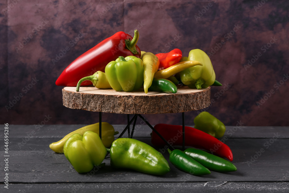 Board with different fresh peppers on black wooden table