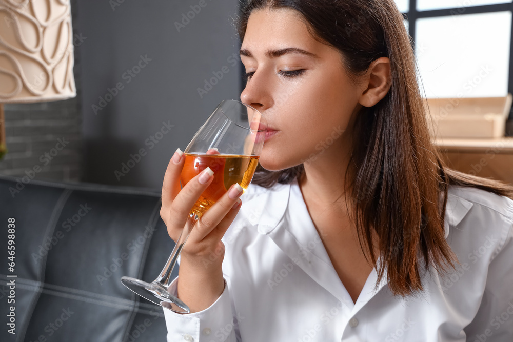 Young woman drinking wine on couch at home, closeup