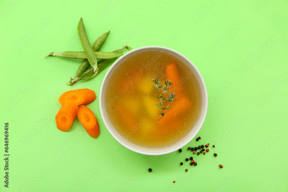 Bowl of tasty vegetable broth on green background